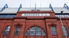 Frontalansicht der unter Denkmalschutz stehenden, roten Backsteinfassade der Haupttribüne mit dem markanten weißen Schriftzug „RANGERS F.C.“.